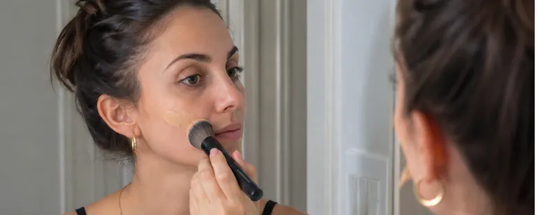 Woman applying makeup in the mirror