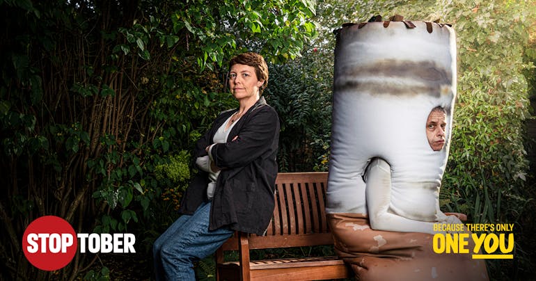 Woman with steely resolve sitting on a bench with a ugly half man / half cigarette hybrid.