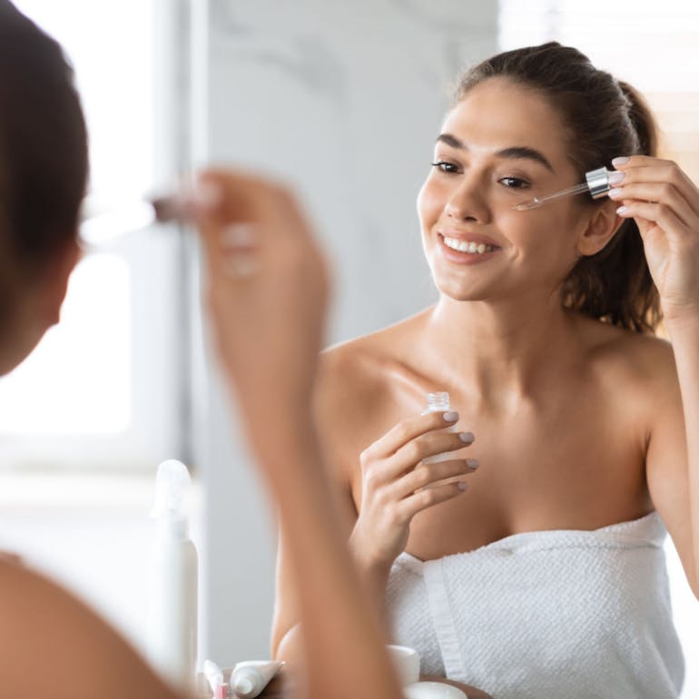 woman-applying-skincare-product-mirror