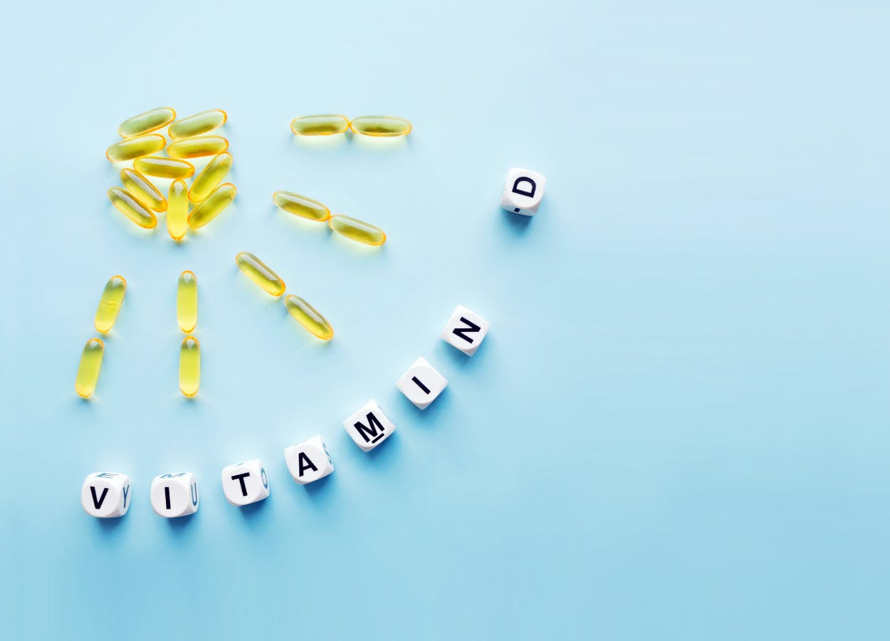 Pill capsules in the shape of a sun and text: 'Vitamin D'